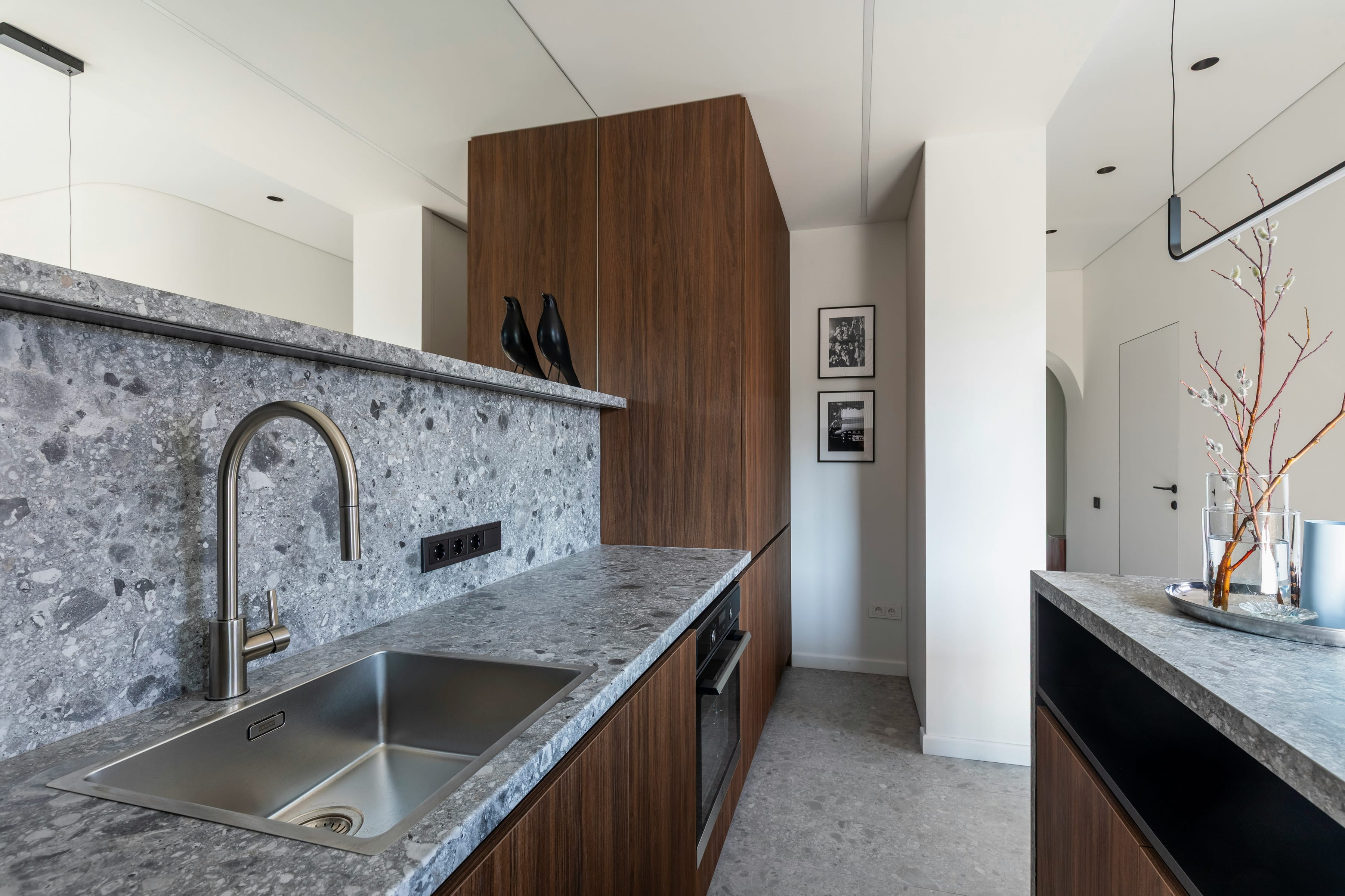 Narrow kitchen with terrazzo splashback, walnut tall unit and steel sink