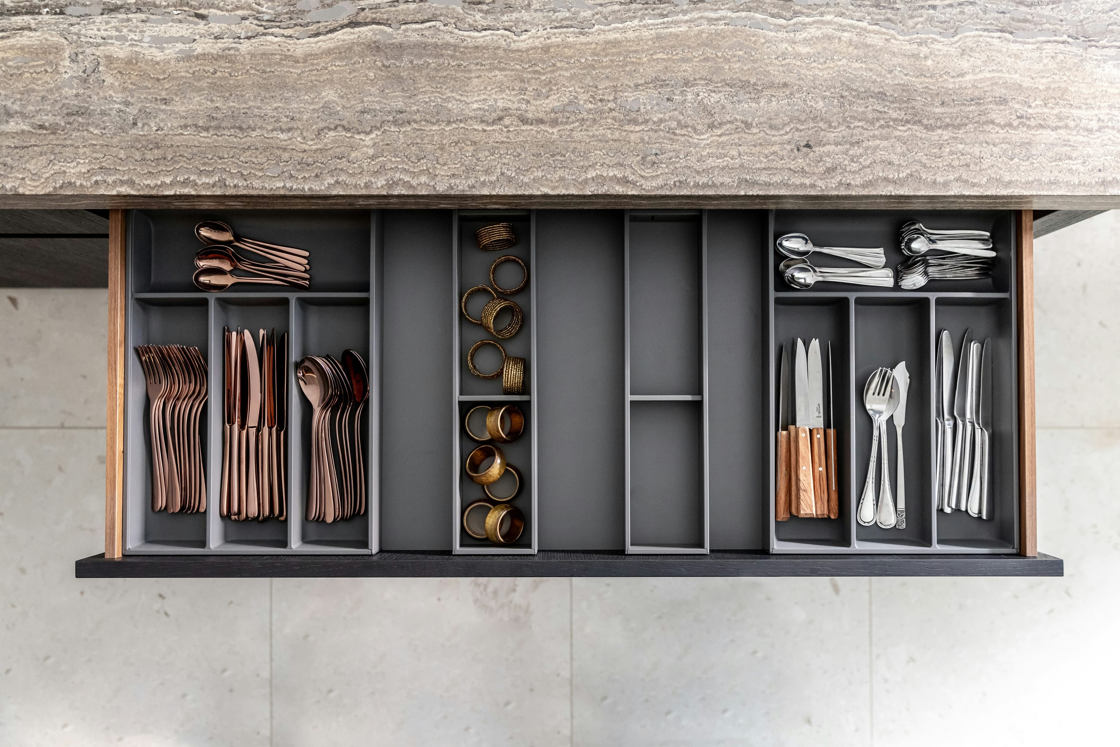 Dark kitchen drawer with cutlery inserts and spice compartments, top view