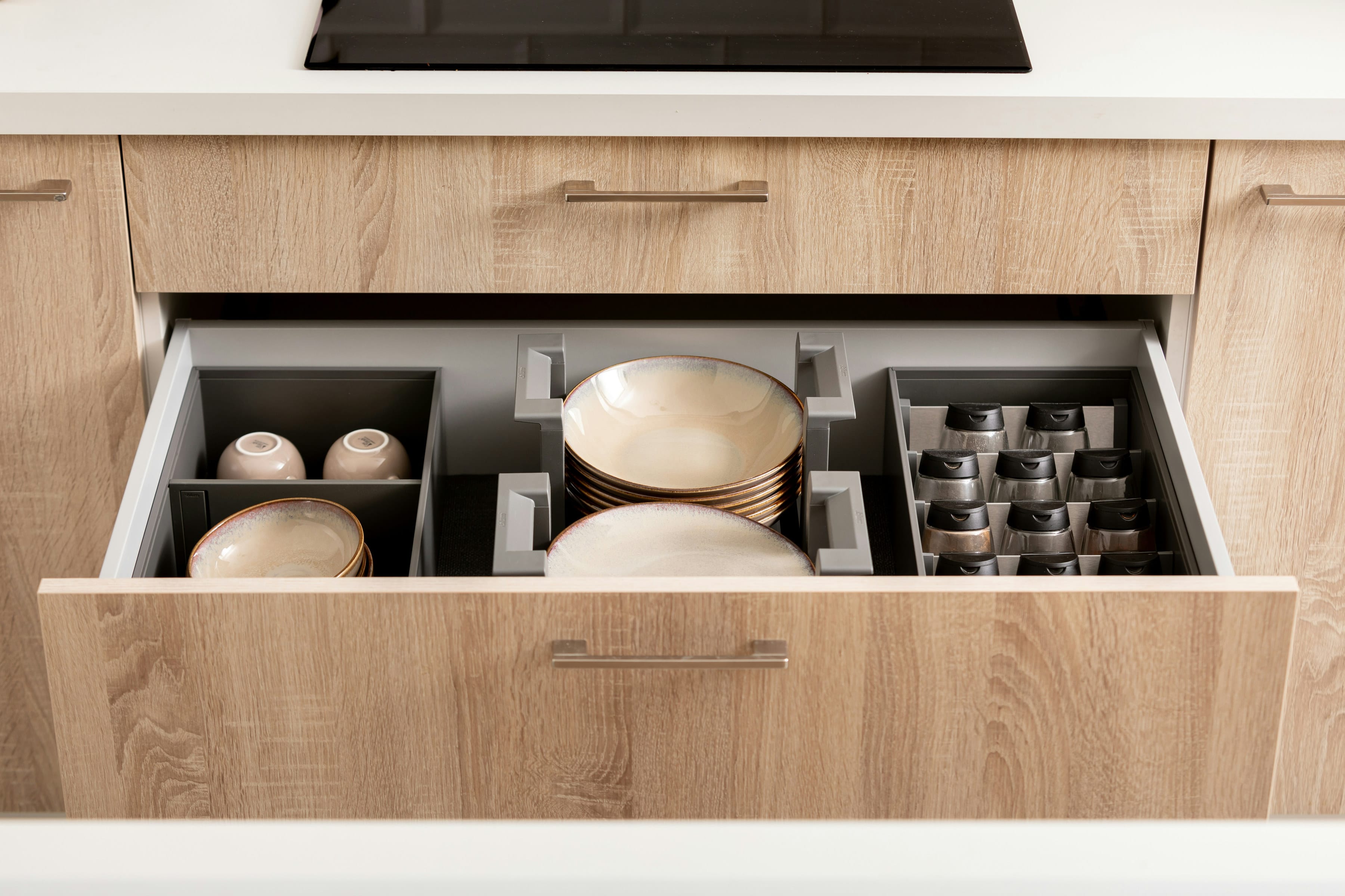 Open oak drawer with plates and bowls held in dividers