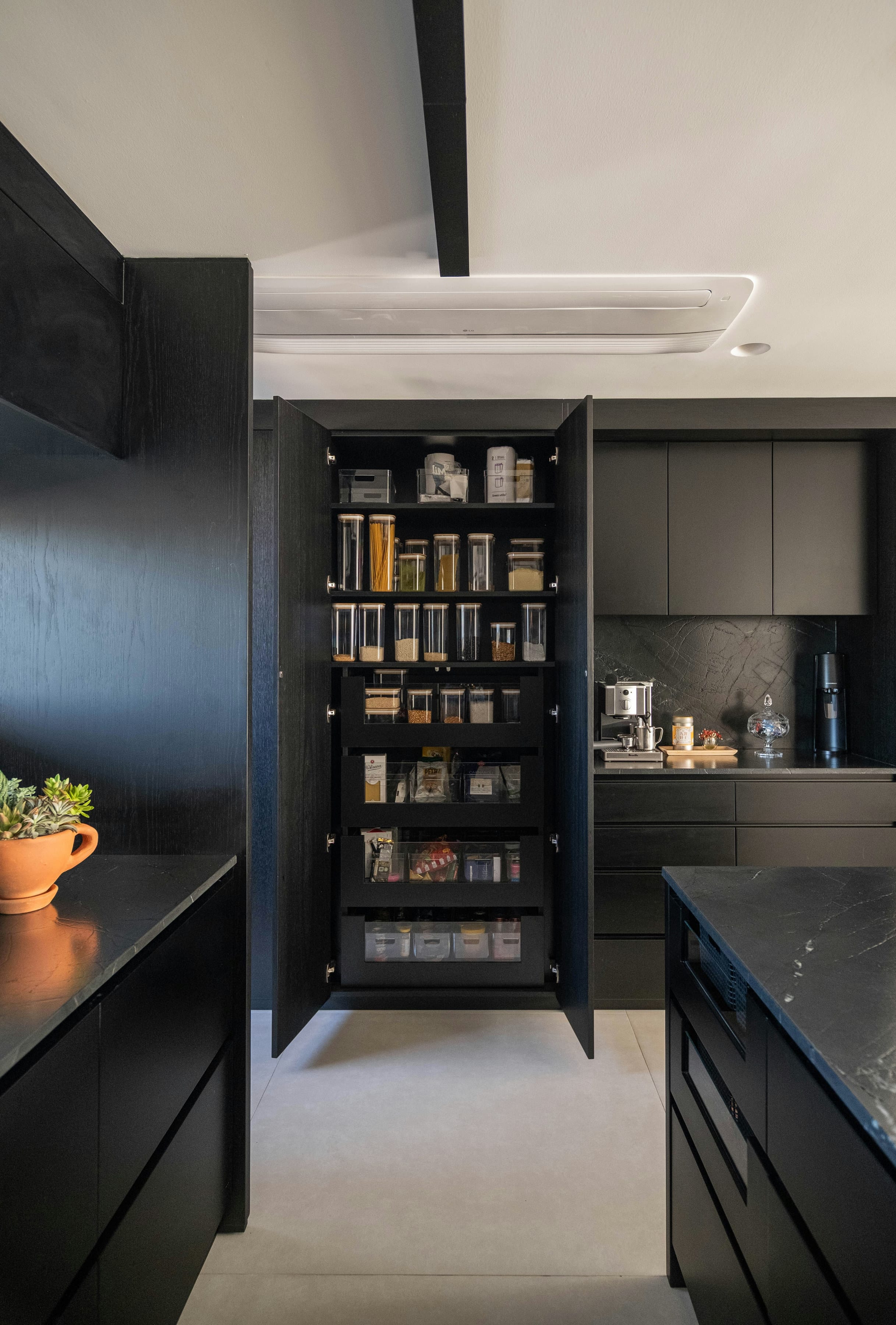 Black pantry cabinet opened to show jars and organised shelves