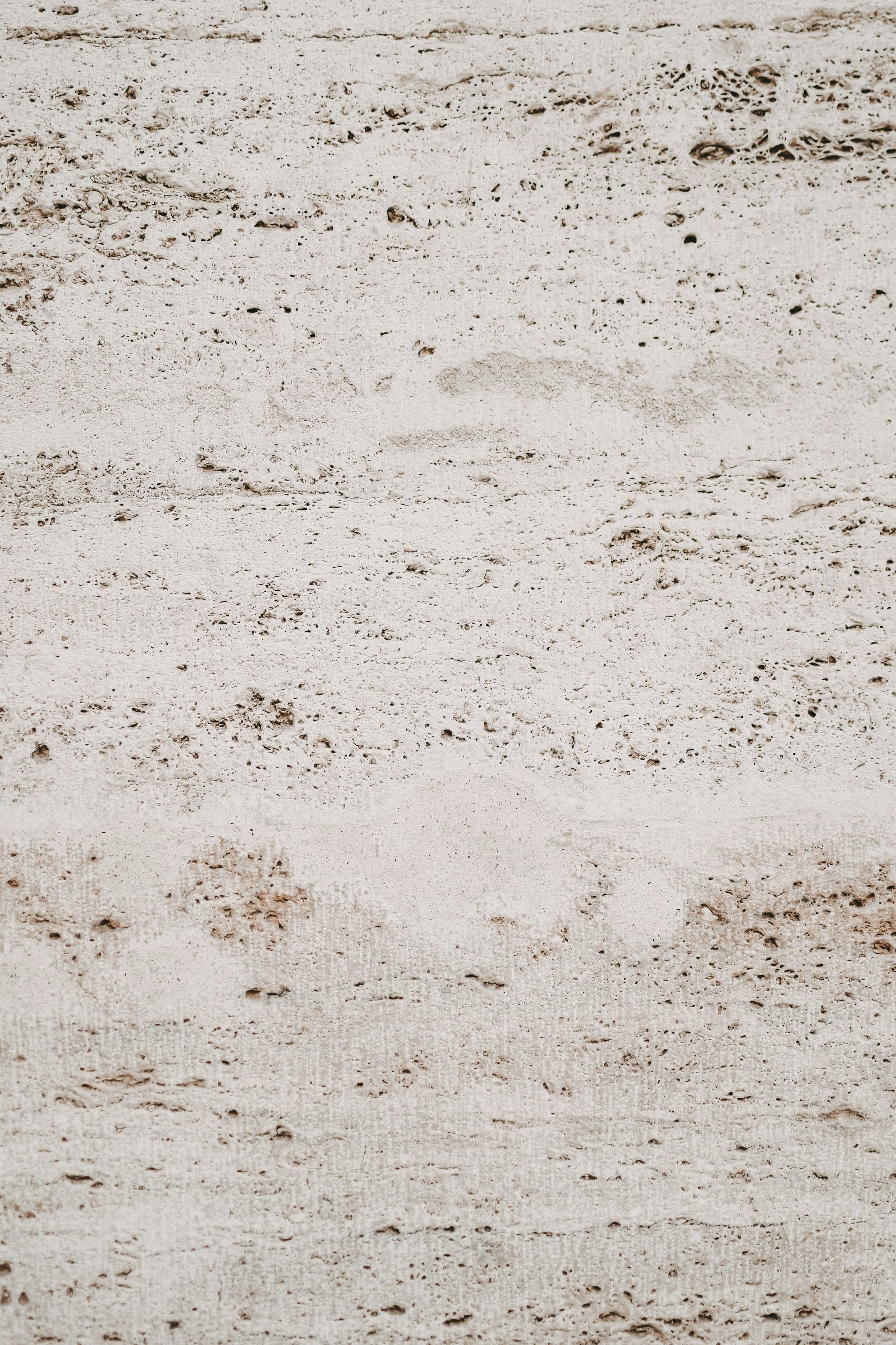 Pale travertine surface with soft brown pitting and warm beige tone