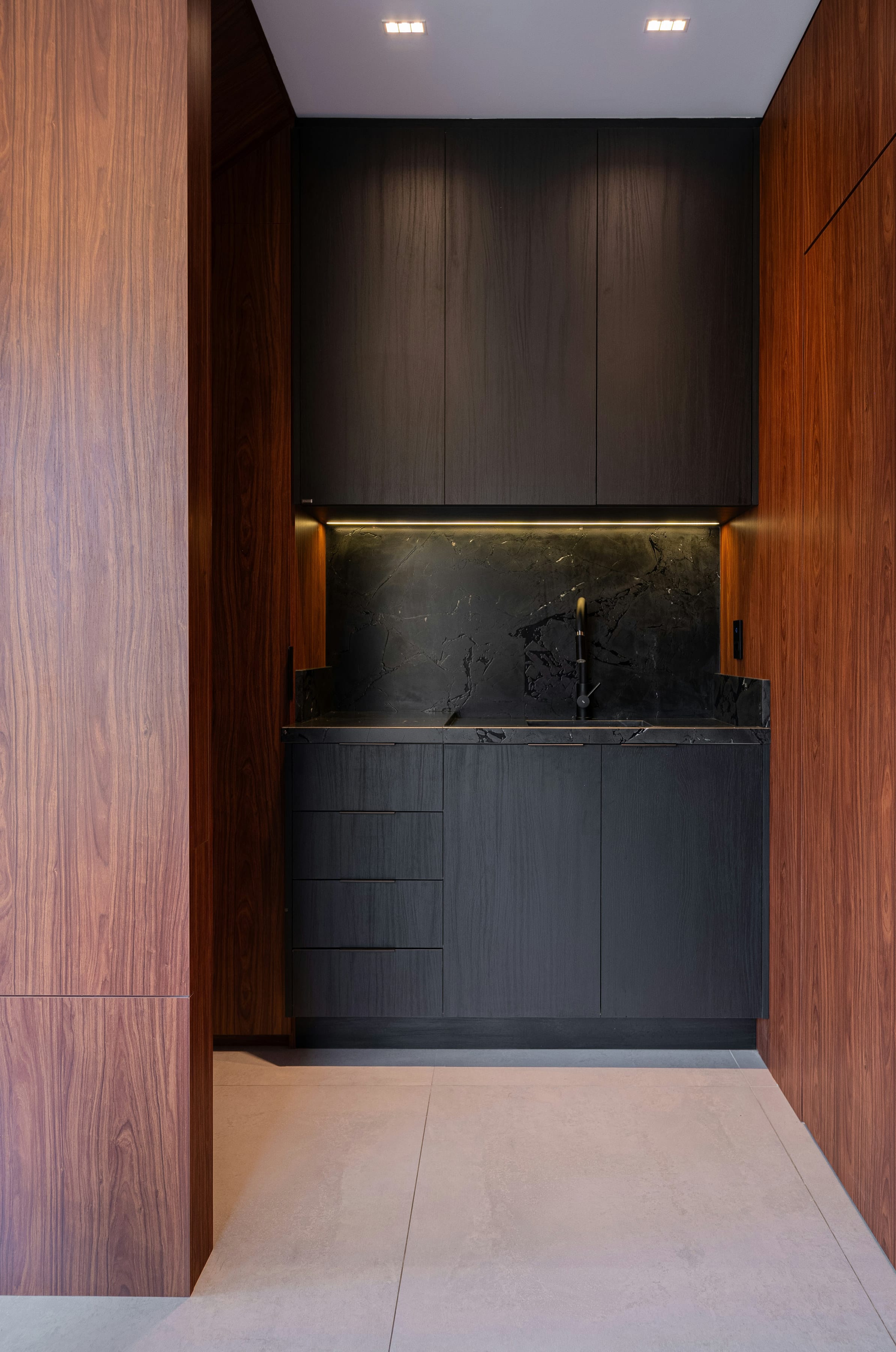 Walnut-framed black marble niche with warm LED strip light